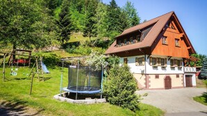 A house with a sloped roof, a trampoline, and a swing set in a grassy area. - Farmhouse 'Weißtanne' with Mountain View, Private Terrace and Wi-Fi (Oberkirch)