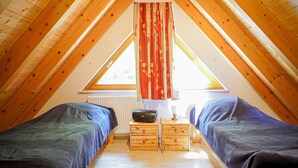 A small attic bedroom with two single beds, wooden headboards, a radiator, a radio, and a window with curtains. - Farmhouse 'Weißtanne' with Mountain View, Private Terrace and Wi-Fi (Oberkirch)