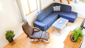 A living room with a blue sofa, a wooden coffee table, a brown chair, and two potted plants. - Farmhouse 'Weißtanne' with Mountain View, Private Terrace and Wi-Fi (Oberkirch)