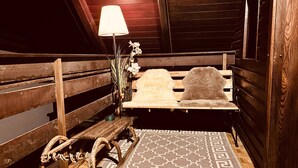 Un banc en bois avec un coussin moelleux, une lampe et un vase rempli de fleurs, le tout placé dans un coin.