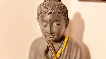 A statue of a seated figure with a textured head and a draped garment.