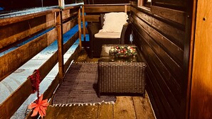 Une cabane en bois dotée d’un balcon, d’un banc et d’une petite table décorée pour Noël.