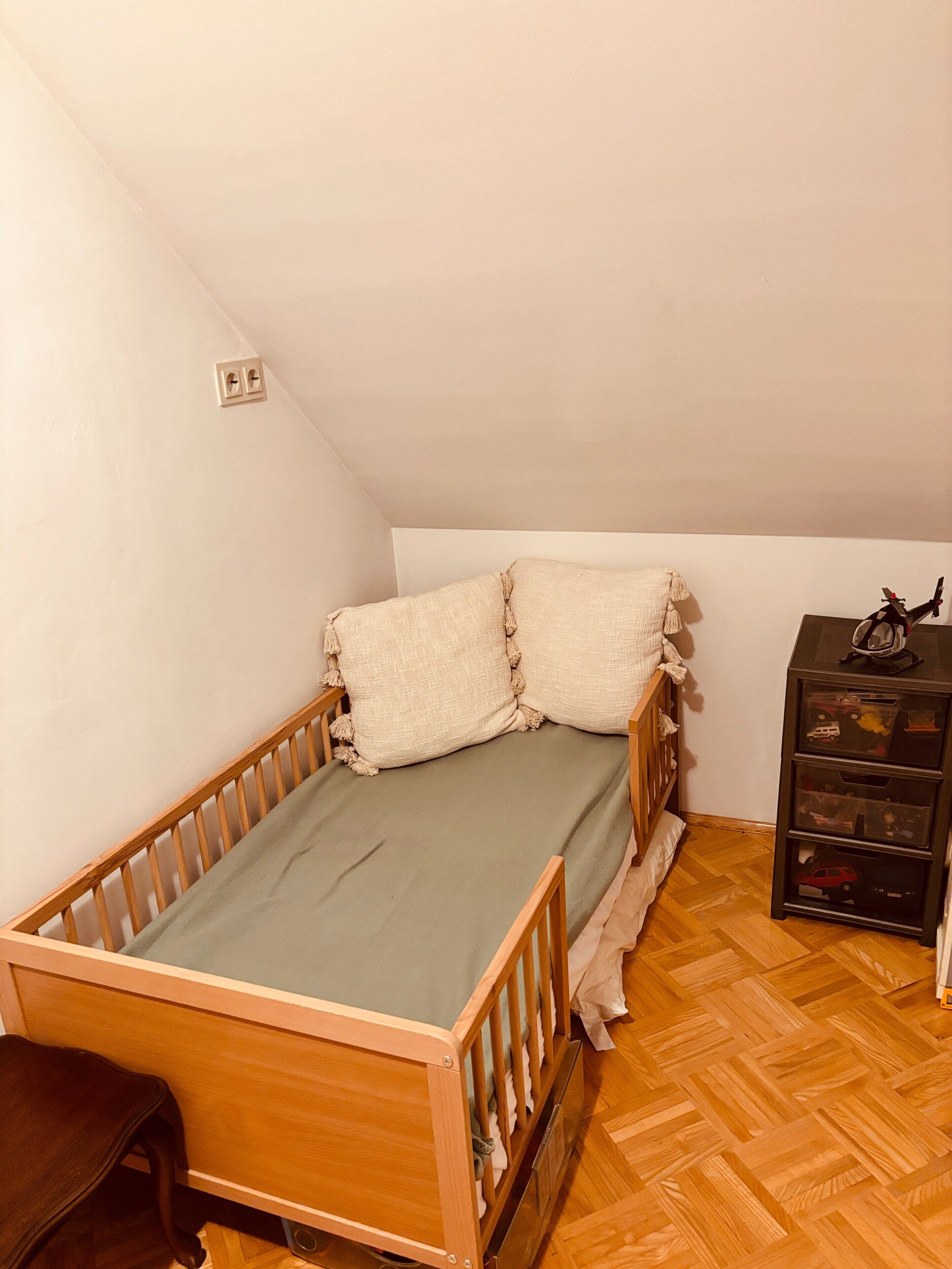 Ein kleines Zimmer für eine Person mit einem hölzernen Etagenbett, einem kleinen Schreibtisch und einer Kommode.