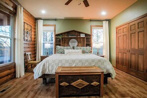 A cozy log cabin bedroom with a large bed, wooden headboard, and a wooden chest of drawers. - Hilltop Haven • Pool, Hot Tub & Game Loft (Fayetteville)