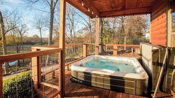 Een hottub op een houten terras, met uitzicht op bomen en een wateroppervlak.
