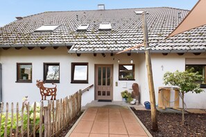 Une maison avec un toit en tuiles, une clôture en bois et un petit jardin.