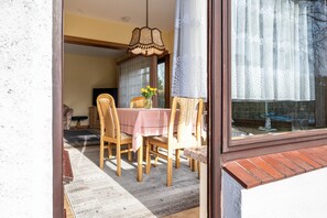A dining area with a table set for four, a vase with flowers, and a window with curtains.