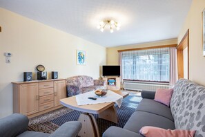 A living room with a sofa, a table, a television, and a cabinet.