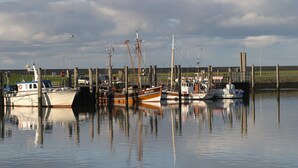 A marina with several boats docked, calm water, and a grassy area in the background. - Holiday Home 'Haus Lahrsen' with Private Terrace, Shared Garden and Wi-Fi (Wesselburen)