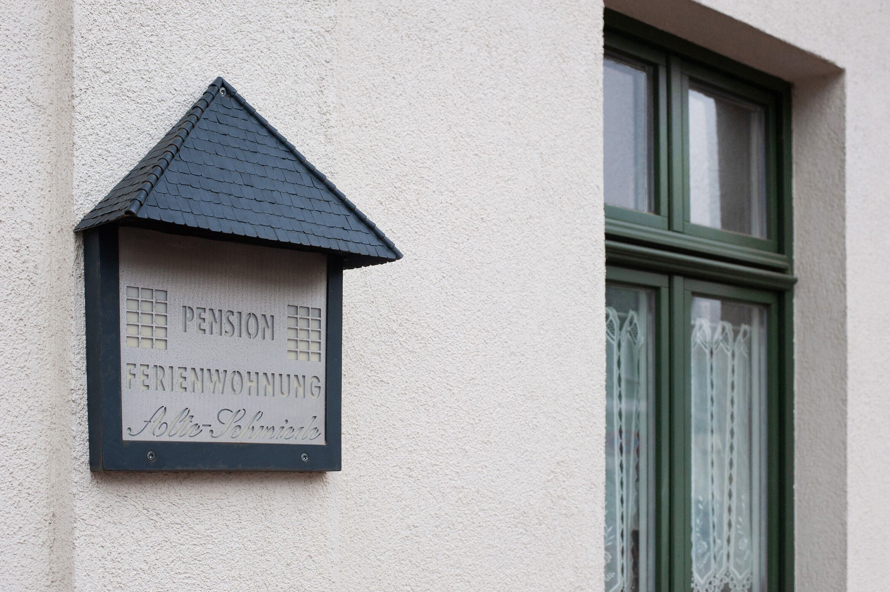 Un cartel de casa con la palabra 'PENSION' y 'FERIENWOHNUNG', indicando una pensión.