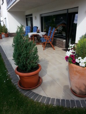 A patio with a table and chairs, potted plants, and a brick wall. - Apartment 'Poll' with Private Terrace, Private Garden and Wi-Fi (Wimbach)