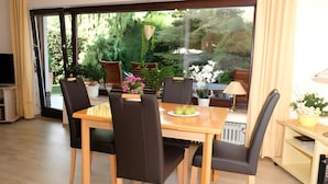 A dining area with a table, chairs, and a view of greenery outside. - Apartment 'Poll' with Private Terrace, Private Garden and Wi-Fi (Wimbach)