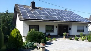 A house with a solar panel roof, a paved driveway, and potted plants. - Apartment 'Poll' with Private Terrace, Private Garden and Wi-Fi (Wimbach)