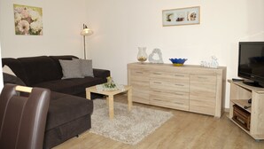 A living room with a sofa, a coffee table, a TV stand, and a cabinet. - Apartment 'Poll' with Private Terrace, Private Garden and Wi-Fi (Wimbach)