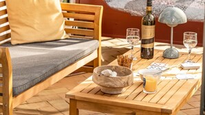 Ein Holztisch mit einer Weinflasche, Gläsern, einer Schale mit Snacks und einer Karaffe Orangensaft.