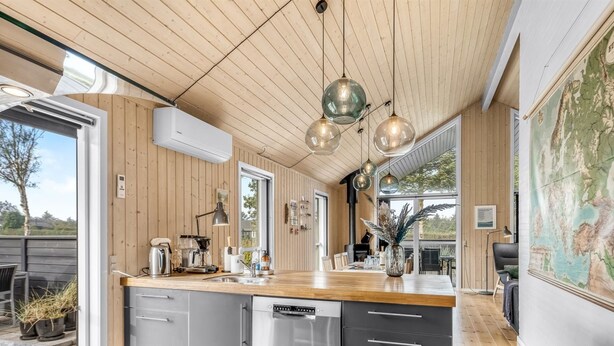 Eine moderne Küche mit Holzverkleidung, einer großen Kochinsel mit Spüle und Pendelleuchten.