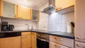 Een moderne keuken met houten kastjes, een zwart aanrecht en roestvrijstalen apparatuur, inclusief een inbouwoven.