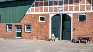 Een bakstenen gebouw met een groene deur, een kleine tafel met een bloempot en een bord boven de deur.