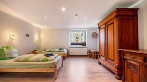 Een slaapkamer met twee bedden, een houten kast, een raam met uitzicht en een radiator.