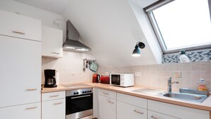 A modern kitchen with white cabinets, a stove, a microwave, and a sink. - Apartment 'Ferienwohnung Abendsonne' with Wi-Fi (Lehe)
