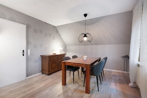 Un comedor con una mesa de madera, sillas, una lámpara colgante, un armario y una puerta.