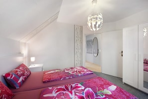 Un dormitorio con cama, mesita de noche, armario y puerta que da a otra habitación.