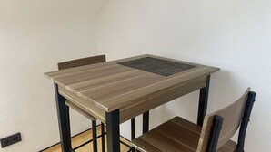A small dining table with a woven placemat, black metal legs, and a wooden chair. - Holiday Apartment 'An Der Galopprennbahn' with Wi-Fi (Iffezheim)