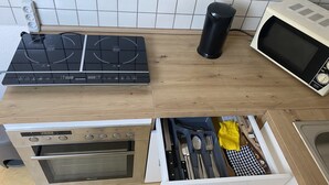 A kitchen with a stove, microwave, and a drawer with utensils. - Holiday Apartment 'An Der Galopprennbahn' with Wi-Fi (Iffezheim)