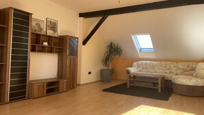 A loft-style room with a wooden floor, a sofa, a coffee table, a large plant, and a skylight. - Holiday Apartment 'An Der Galopprennbahn' with Wi-Fi (Iffezheim)
