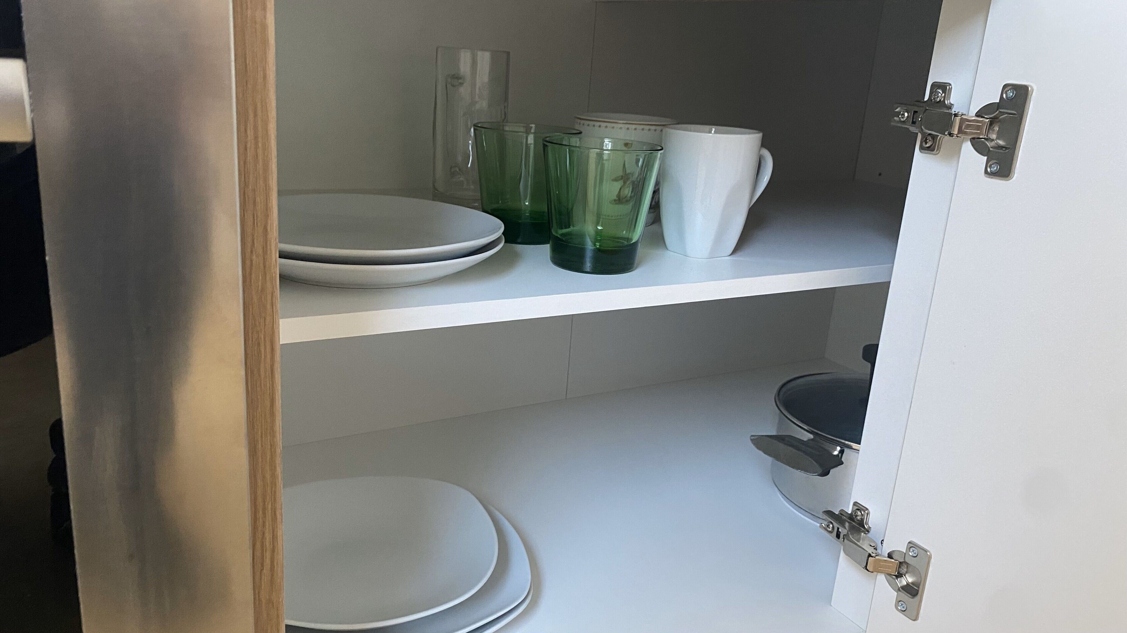 Een keuken met witte kasten, een roestvrijstalen deur en een wit aanrecht.