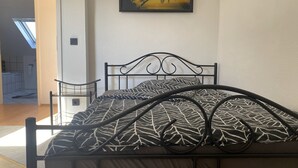 A bed with a patterned bedspread, a headboard, and a metal frame. - Holiday Apartment 'An Der Galopprennbahn' with Wi-Fi (Iffezheim)