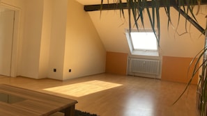 Una habitación con techo inclinado, tragaluz, radiador y suelo de madera.