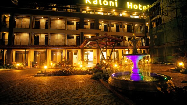 Egy „Kaloni Hotel” nevű szálloda, amelynek fényesen világító táblája, egy szökőkútja és egy kiépített bejárati területe van.