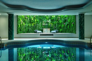 A luxurious indoor pool area with a green wall and two lounge chairs. - Hotel Tamisa (Mijas)