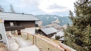 A modern building with a wooden staircase and a metal railing, overlooking a mountainous landscape. - Daniele by Interhome (Mühlbach am Hochkönig)