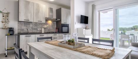 Een moderne keuken met een groot eiland, inbouwapparatuur en een aan de muur bevestigde televisie.