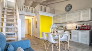 A modern kitchen with white cabinets, a red microwave, and a clock on the wall. - Onda perfetta by Interhome (Valledoria)