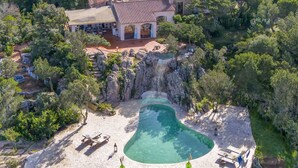 Un resort con piscina, cascada y un edificio de techo de tejas.