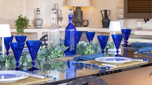 Una mesa de comedor dispuesta con cristalería azul, platos blancos y un centro de mesa decorativo.