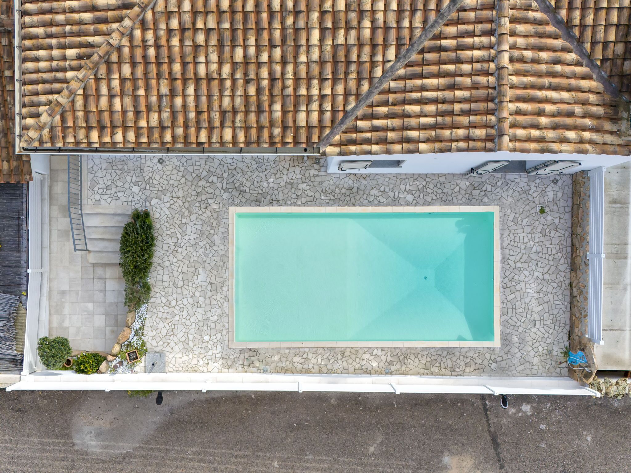 A rooftop swimming pool with a tiled roof and a stone mosaic border.