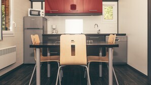 Una cocina compacta con una isla central, dos sillas, microondas, cafetera y lavavajillas.