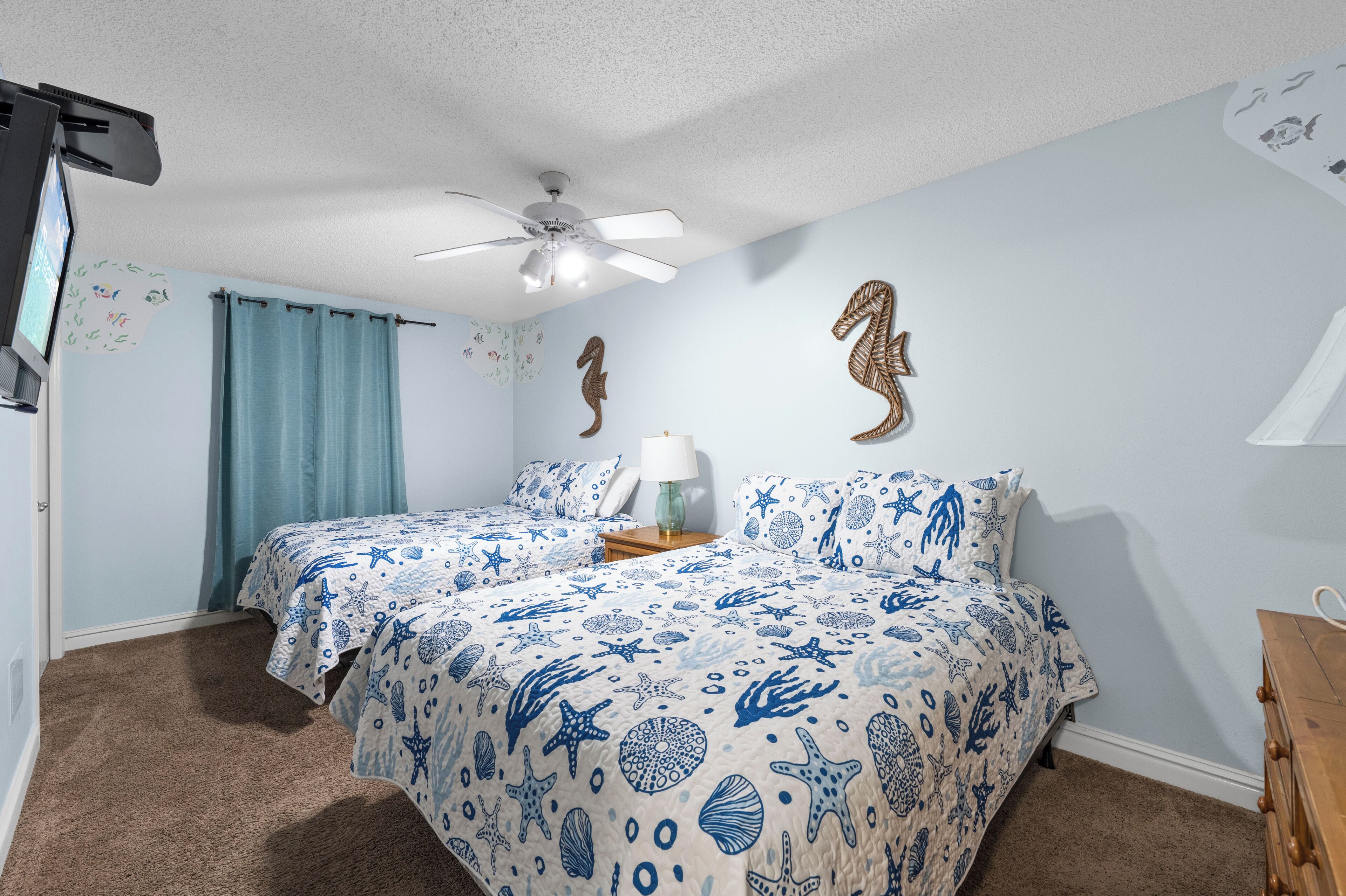 A bedroom with two beds, a ceiling fan, and decorative wall art.