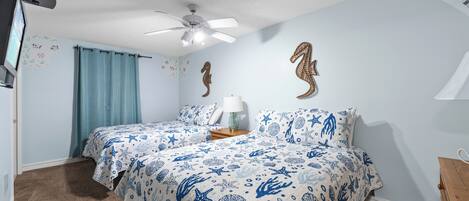 A bedroom with two beds, a ceiling fan, and decorative wall art.