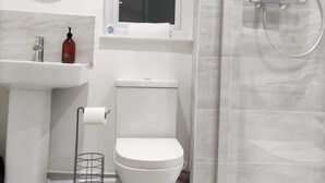A modern bathroom with a toilet, sink, and shower.