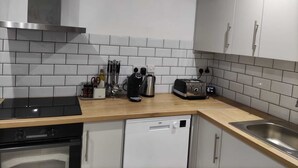 A modern kitchen with white cabinets, a stainless steel sink, a toaster, and a dishwasher.