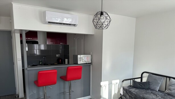 A modern kitchen with a microwave, red bar stools, and a hanging light fixture. - Full center  (Le Malesherbois)