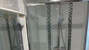 A modern bathroom with a glass-enclosed shower, a white sink with a marble countertop, and a mirror above the sink. - Full center  (Le Malesherbois)