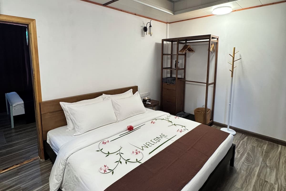 A hotel room with a bed, a ceiling fan, a wardrobe, and a mirror.