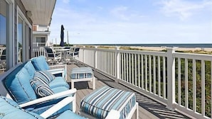 Eine Terrasse mit Sitzgelegenheit und Blick auf den Strand.