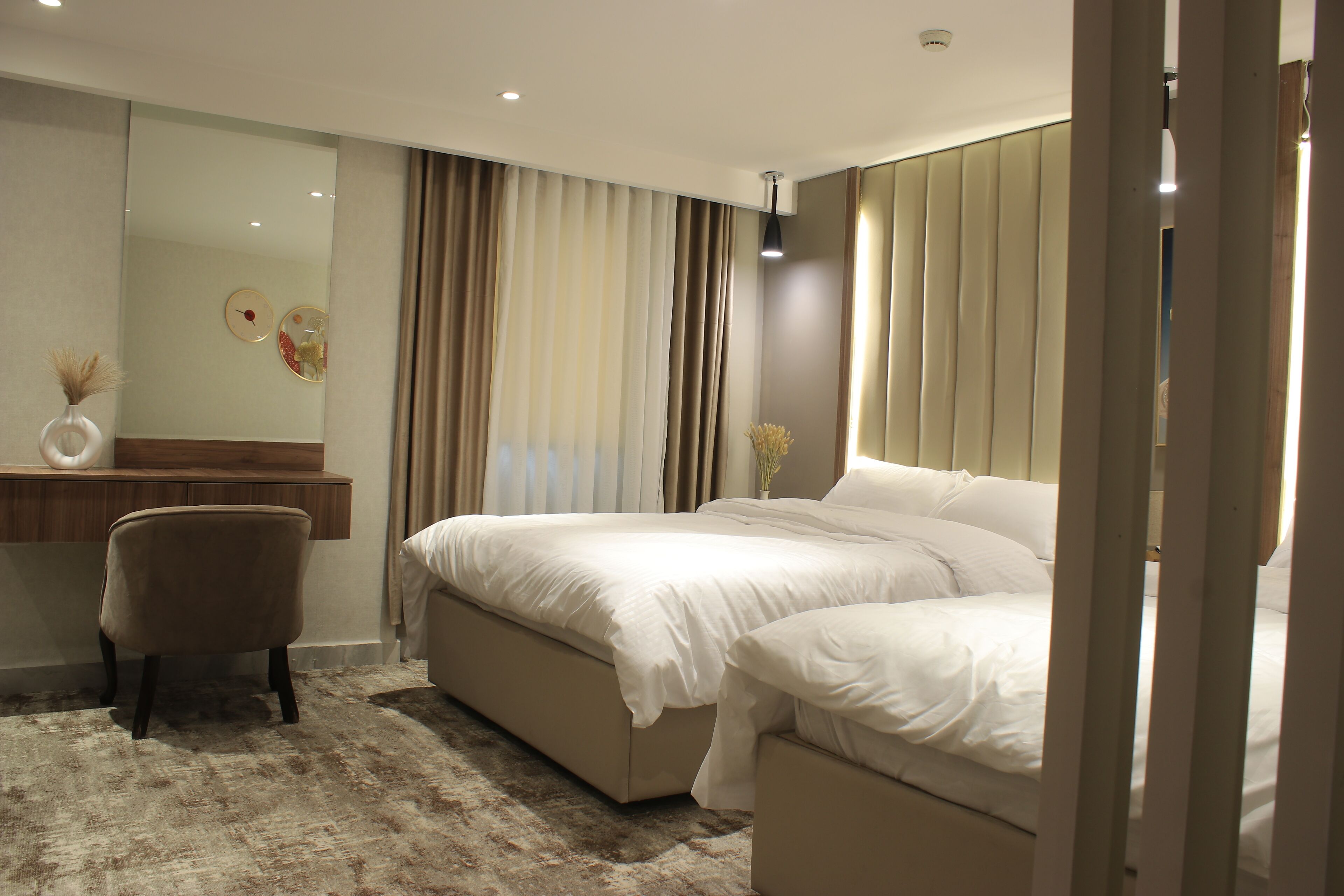 A modern bedroom with a large bed, a bedside table, a chair, and a mirror.